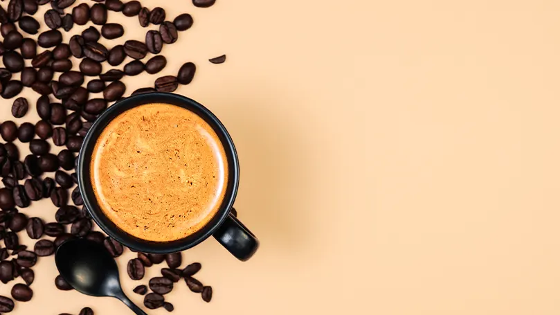 Immagine di una tazza di caffè e di alcuni chicchi di caffè su un tavolo