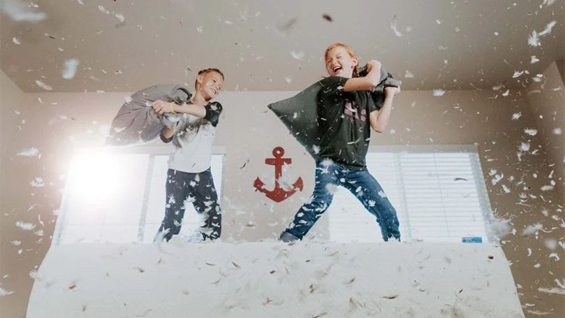 bambini che giocano con cuscini di piume e piumini