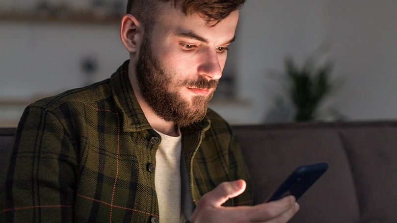 Un'immagine di un uomo che guarda il suo telefono prima di dormire