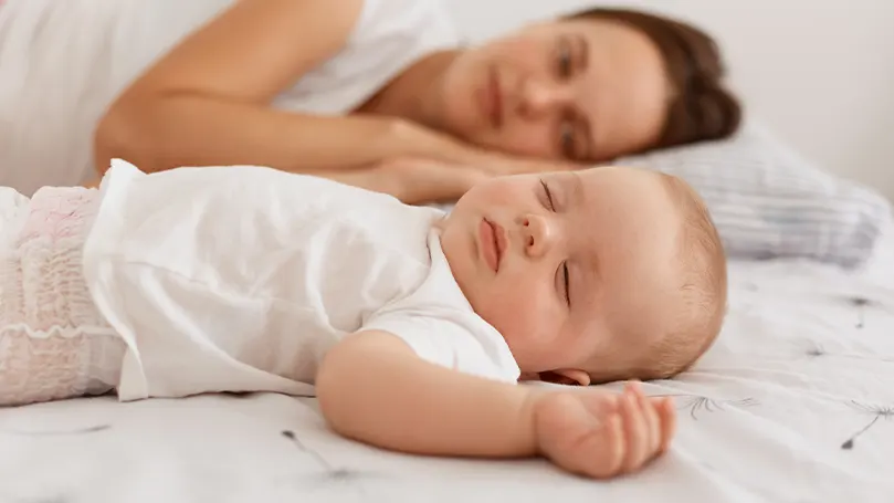 Un'immagine di un bambino che dorme accanto alla mamma.