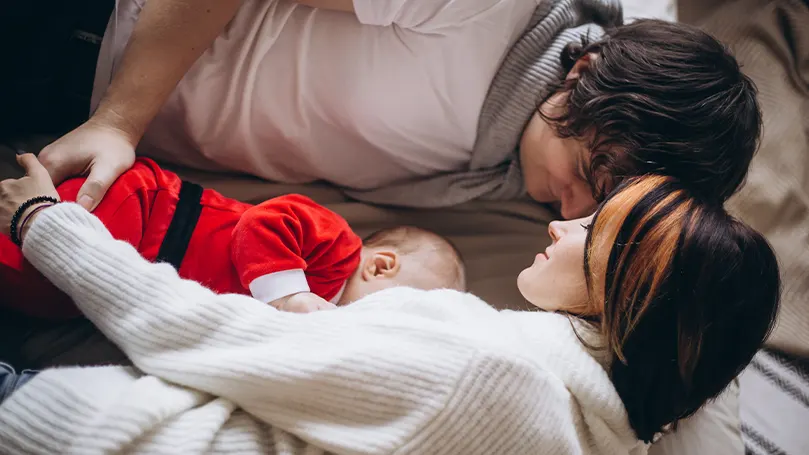 Immagine di un bambino che dorme tra i genitori.