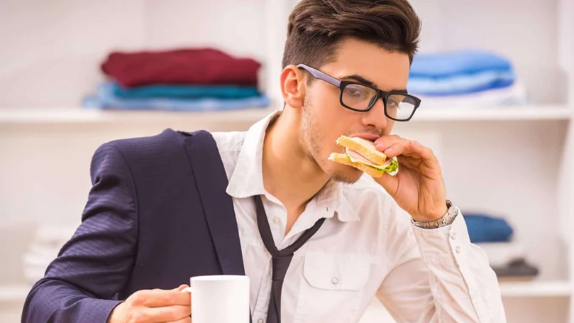 l'immagine di un uomo che mangia velocemente per arrivare in tempo al lavoro