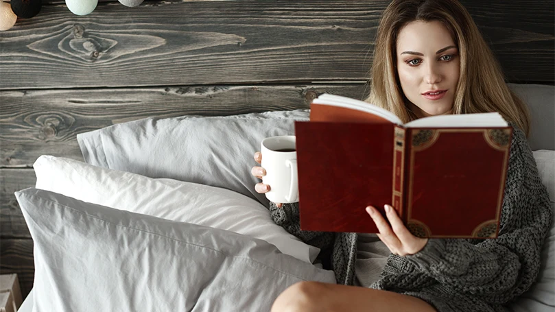 Un'immagine di una donna che legge un libro a letto