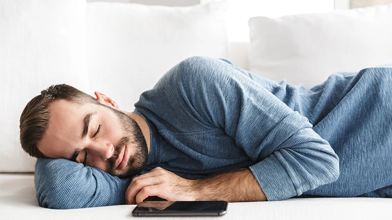 l'immagine di un uomo che dorme accanto al suo cellulare