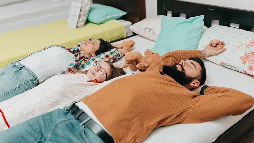 Immagine di una giovane famiglia sdraiata su un materasso con rivestimento in gel.