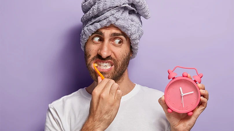 L'immagine di un uomo che si è svegliato tardi, guardando l'orologio e lavandosi i denti.