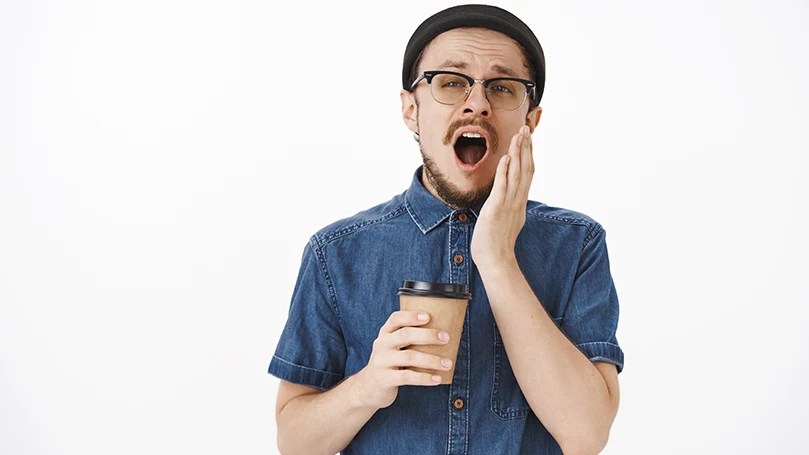 Un giovane uomo che sbadiglia prima di un pisolino al caffè