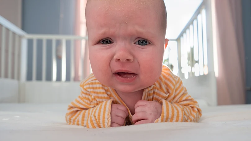 Immagine di un bambino che piange in una culla.