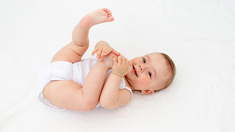 Un bambino sdraiato sulla schiena e sorridente.