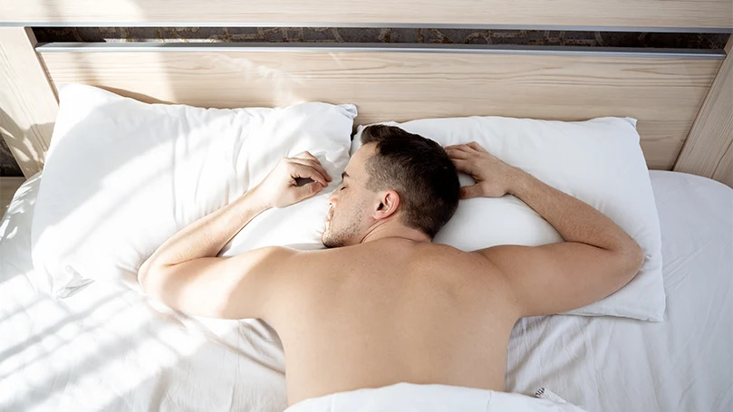 un uomo che dorme a pancia in giù nel suo letto.