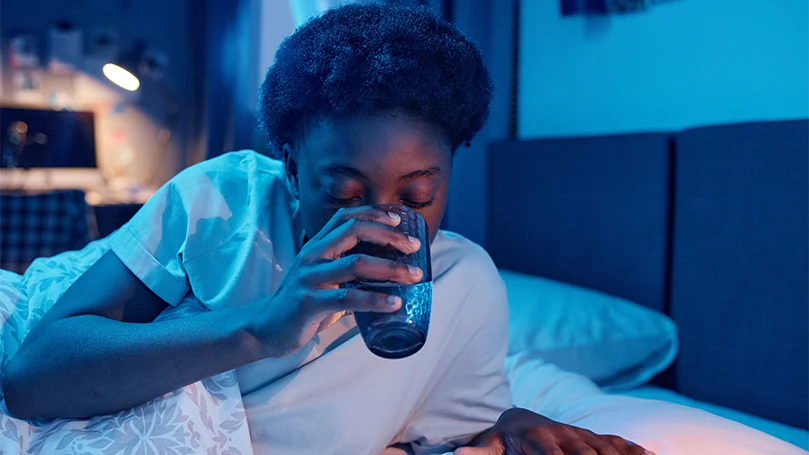 Immagine di una donna che beve un bicchiere d'acqua prima di andare a letto.