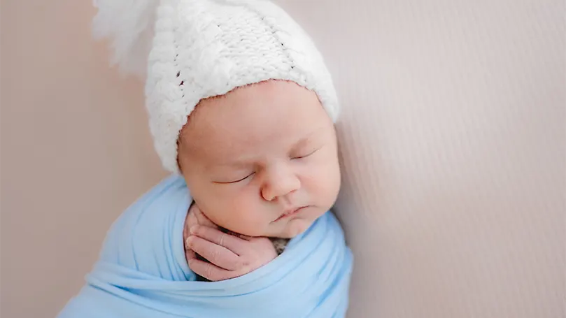 Immagine di un bambino che indossa un cappello mentre dorme.