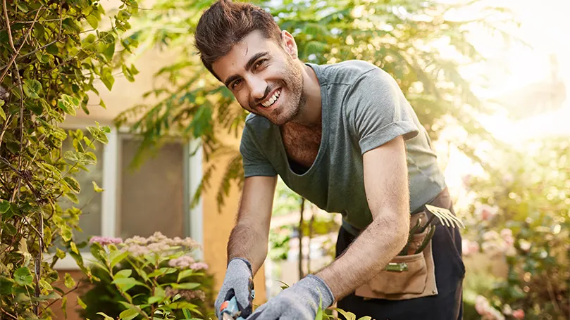 Immagine di un uomo che lavora in giardino sotto la luce del giorno.