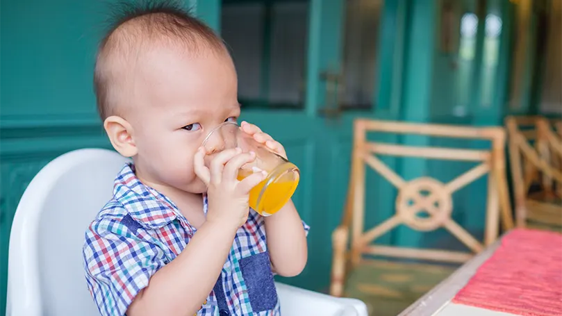 Un'immagine di un bambino di 18 mesi che beve un succo di frutta.