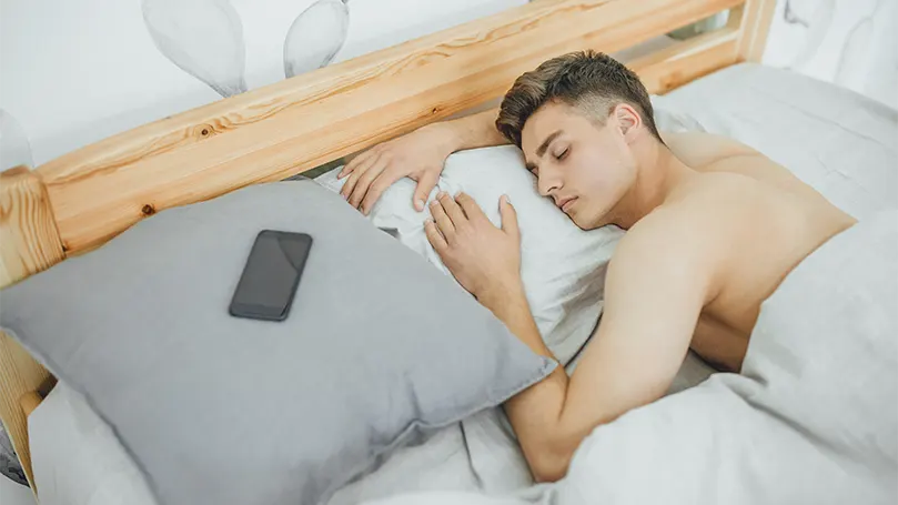 Un'immagine di un uomo giovane e bello che dorme profondamente nel suo letto.