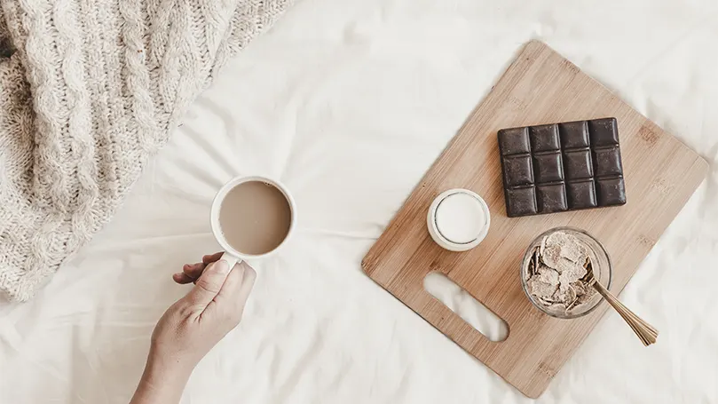 Una mano che tiene una tazza di cioccolata calda.