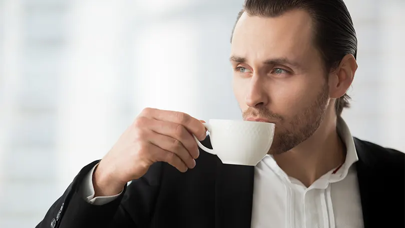 Immagine di un uomo che beve un caffè e sogna ad occhi aperti.