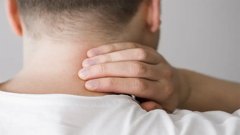 un uomo che si tiene il collo a causa di un dolore cervicale.