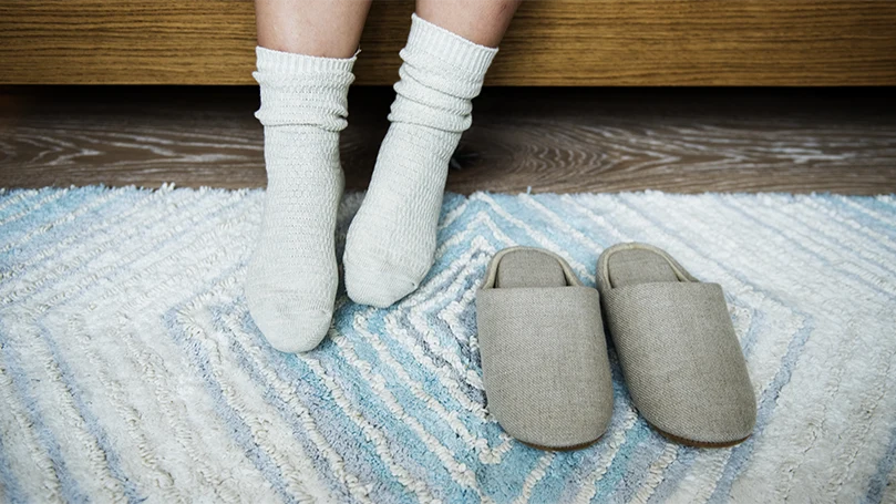 Immagine di una persona che si sveglia e si trova in piedi sul tappeto della camera da letto.