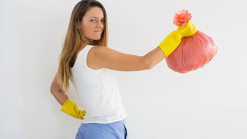 Immagine di una donna che tiene in mano un sacco della spazzatura.