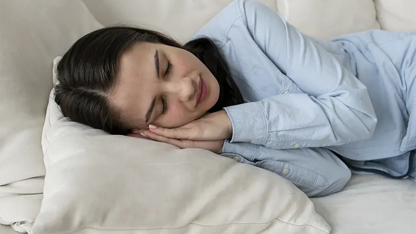 Immagine di una donna che dorme su un divano con uno spazio limitato.