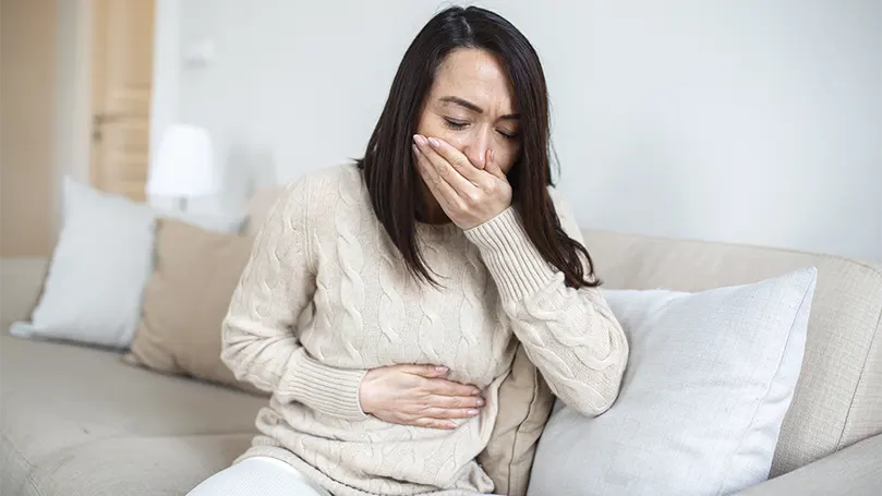 An image of a woman feeling nauseous .