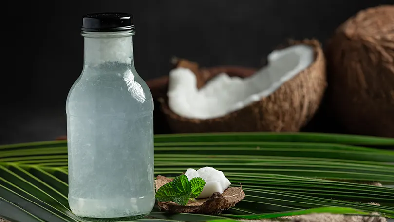 L'immagine di una bottiglia di acqua di cocco davanti a una noce di cocco rotta