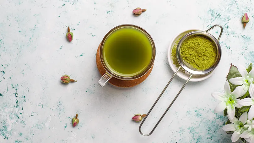 Un'immagine di polvere di matcha accanto a una tazza di tè matcha