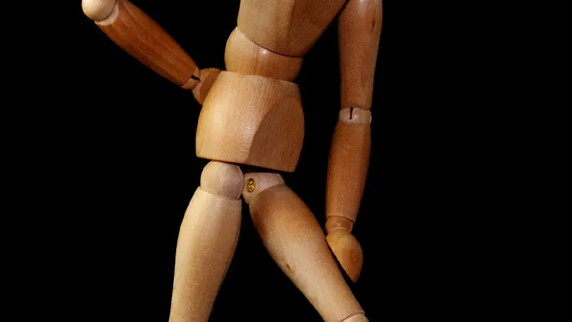 una bambola di legno che simula una posizione con dolore da sciatica