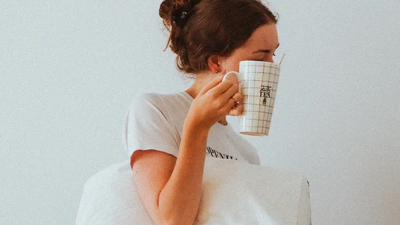 Immagine di una donna che si sveglia dal sonno e beve il tè come parte della sua routine mattutina.