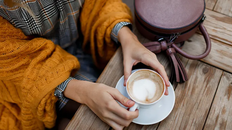 Immagine di una persona che beve caffè all'aperto