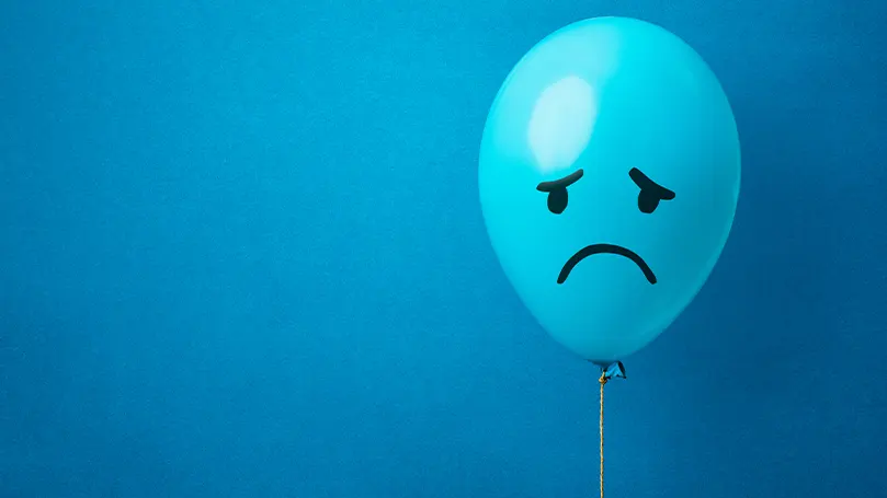 L'immagine di un palloncino blu con disegnata una faccia triste