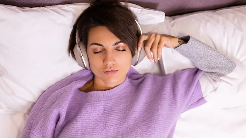 Immagine di una donna a letto con le cuffie in testa