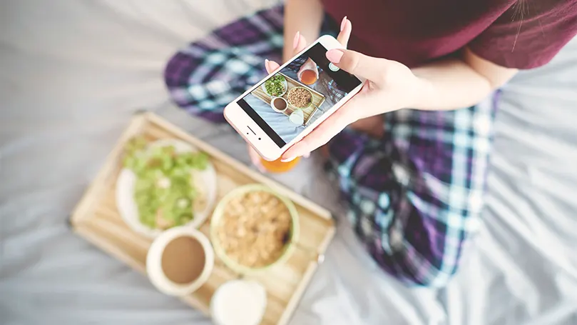 Un'immagine di una persona che mangia sul letto e la fotografa.