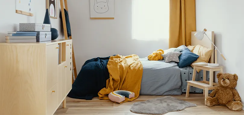 Camera da letto con letto in legno e arredi morbidi blu navy e gialli.