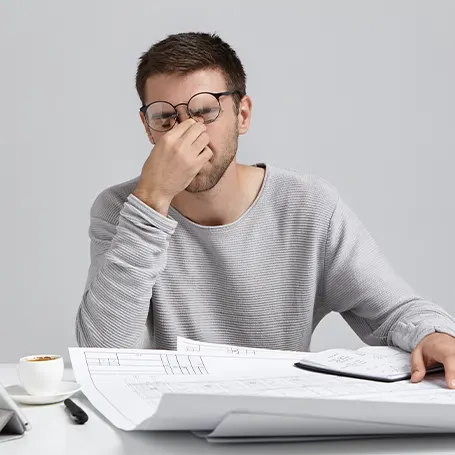 A tired man with glasses sitting at the table