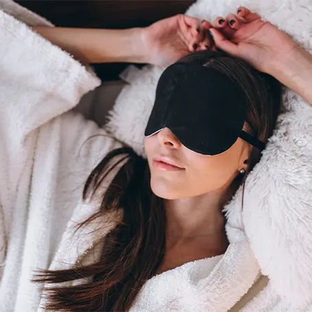 L'immagine di una donna con una maschera per dormire che dorme sulla schiena