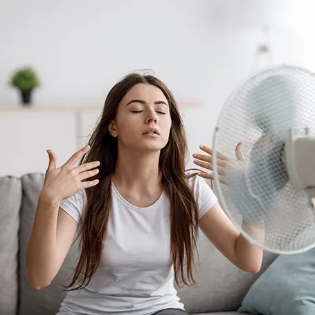 L'immagine di una donna che si rinfresca puntandosi addosso un ventilatore